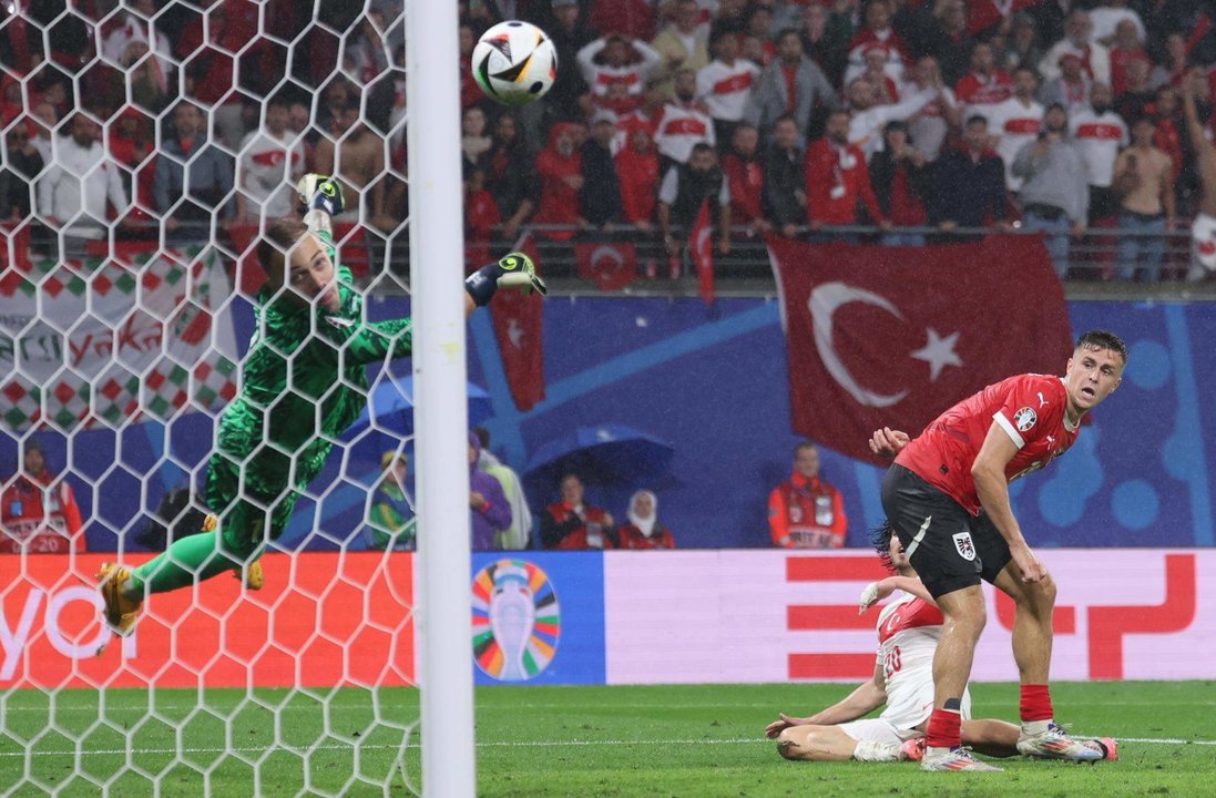 El portero turco Mert Gunok (i) salva un tiro de Christoph Baumgartner de Austria (d) durante el partido de fútbol de la Eurocopa 2024. EFE/EPA/CHRISTOPHER NEUNDORF